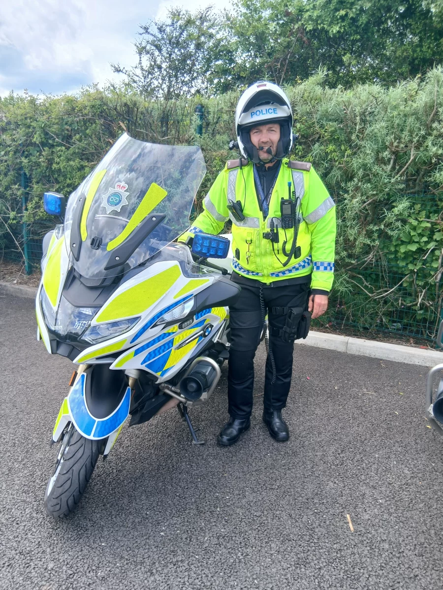 Police motorcyclist standing beside a police motorcycle